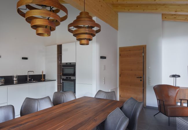 Woonkamer Alm Lodge 4 Woonkamer met tafel en keuken op de achtergrond in Alm Lodge 4