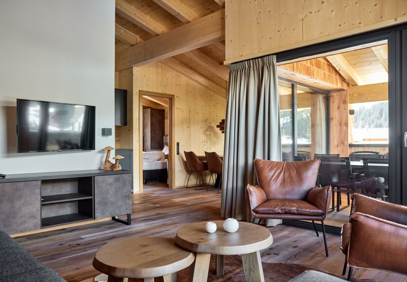 Woonkamer Alm Lodge 8 Woonkamer met bank en fauteuils en de tafel op de achtergrond in de Alm Lodge 8