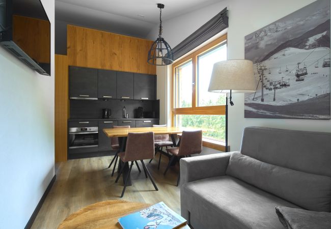 Woonkamer met bank, tafel en keuken in het Bartgeier 118 Alpin-Resort Montafon