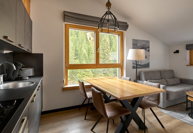 Woonkamer met bank, tafel en keuken in het Bartgeier 219 Alpin-Resort Montafon