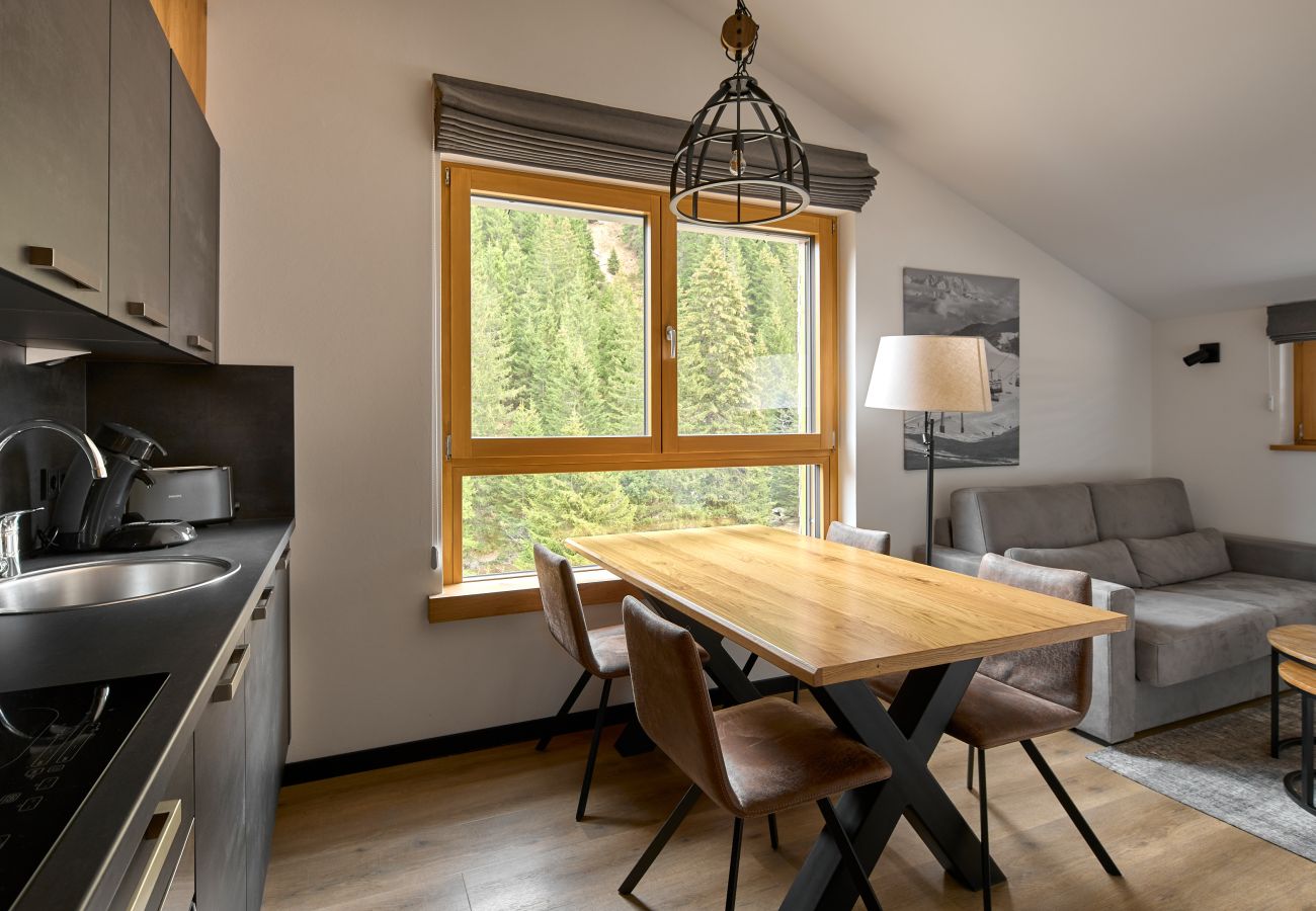 Woonkamer met bank, tafel en keuken in het Bartgeier 219 Alpin-Resort Montafon