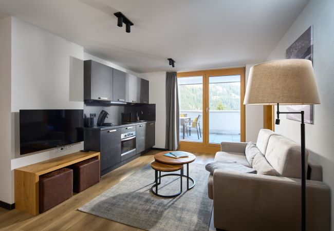 Woonkamer met bank en keuken in het Steinadler 311 Alpin-Resort Montafon