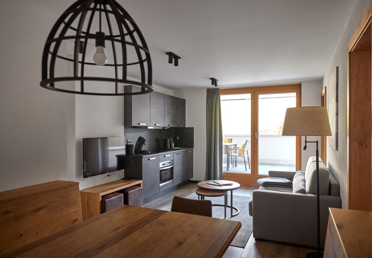Woonkamer met bank, tafel en keuken in het Steinadler 320 Alpin-Resort Montafon