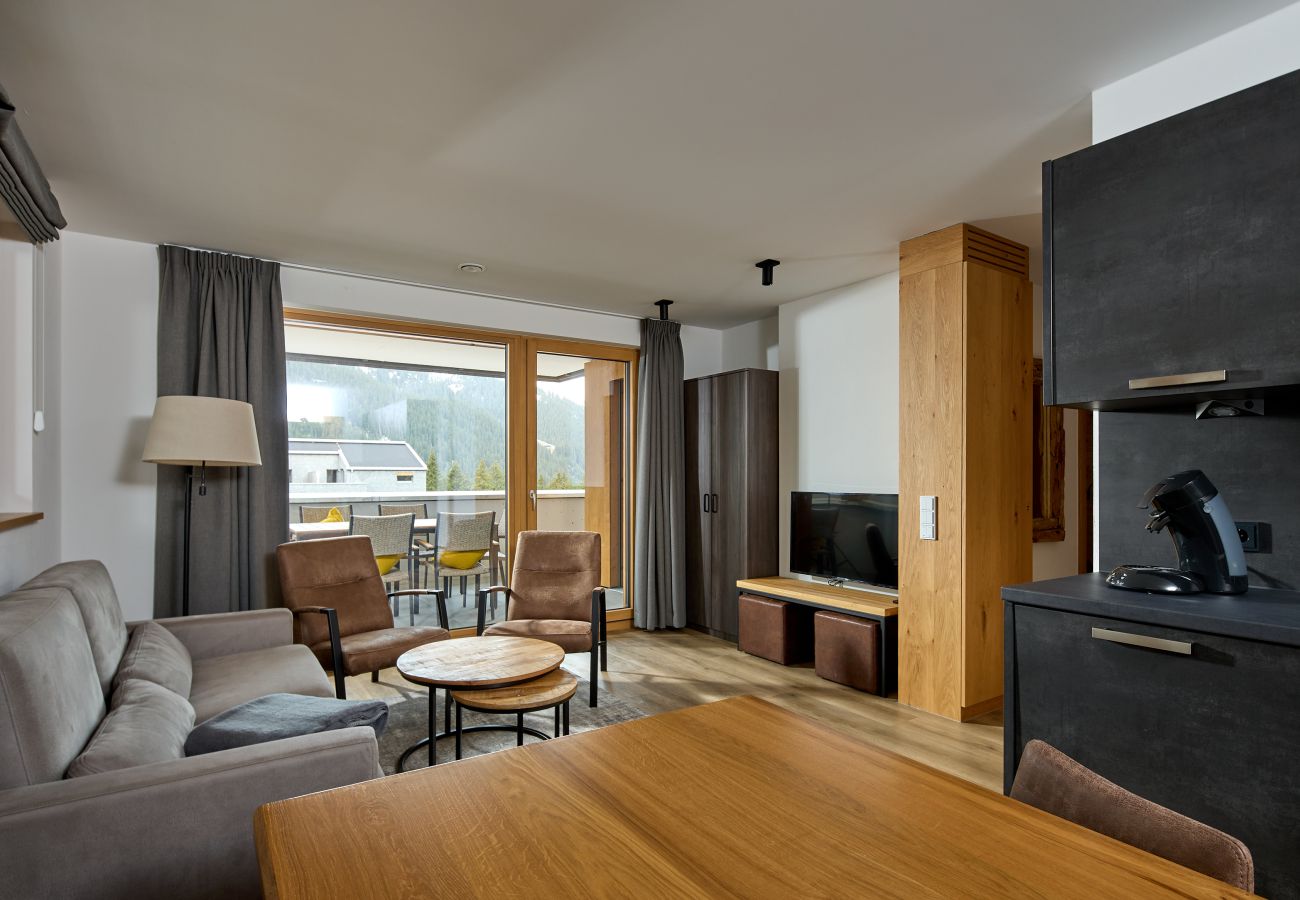 Living area with sofa, table and kitchen in the Bartgeier 211 Alpin-Resort Montafon