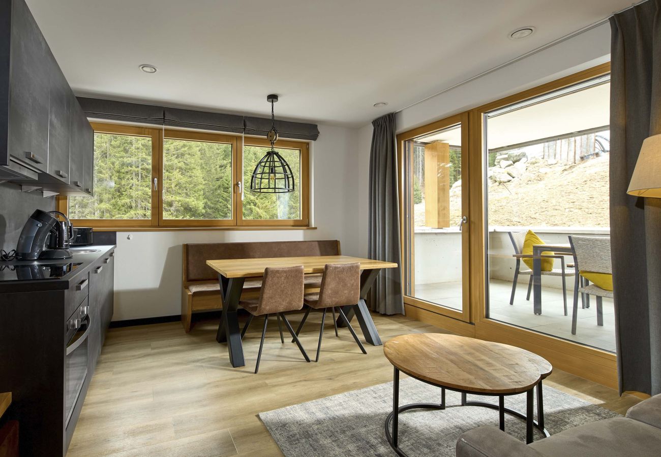 Living area with sofa, table and kitchen in the Fels-Schwalbe 210 Alpin-Resort Montafon