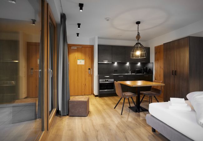 Living area with bed, table and kitchen in the Specht 105 Alpin-Resort Montafon
