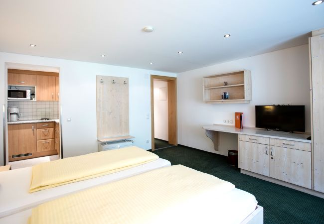 Wohnbereich Andrea Alpenhaus Montafon Schlazimmer mit Doppelbett und einem Fernseher im Andrea Alpenhaus Montafon