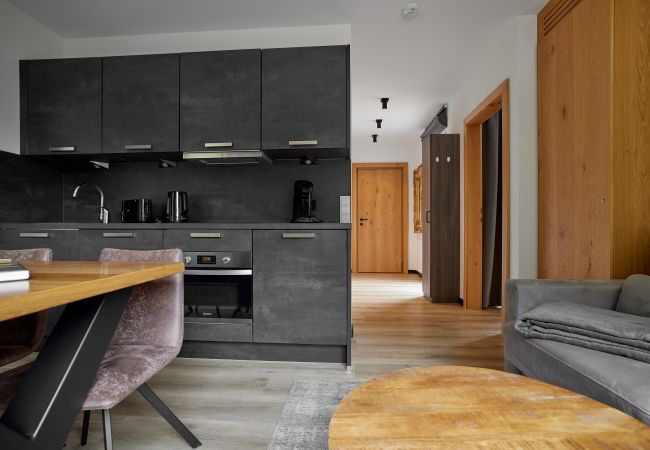 Wohnbereich Wanderfalke 116 Alpin-Resort Montafon Wohnbereich mit Sofa, Tisch und Küche im Wanderfalke 116 Alpin-Resort Montafon