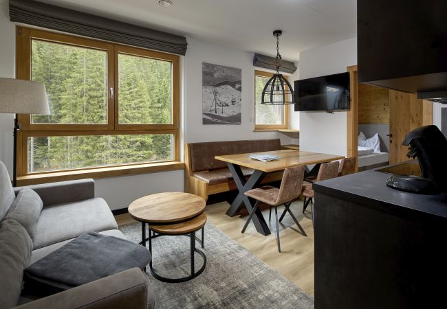 Wohnbereich Wanderfalke 116 Alpin-Resort Montafon Wohnbereich mit Sofa, Tisch und Küche im Wanderfalke 116 Alpin-Resort Montafon