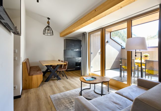 Wohnbereich mit Sofa, Tisch und Küche im Mauerläufer 323 Alpin-Resort Montafon